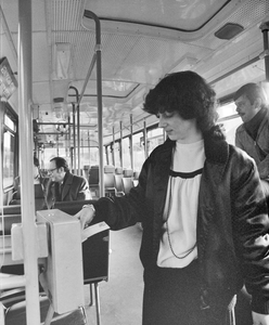 881479 Afbeelding van een vrouw die een strippenkaart afstempelt in de stempelautomaat van een autobus van het G.V.U. ...
